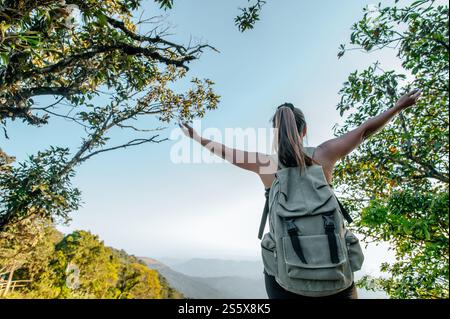 Rückansicht Junge Wanderfrau stehend und aufgerichtet Hände mit glücklich auf dem Gipfel des felsigen Berges, Kopierraum Stockfoto