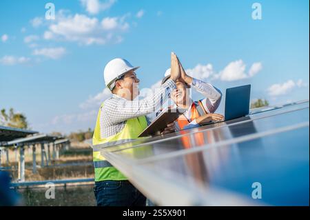 Asiatischer Inspektor Ingenieur Mann mit Check-Board und junger Spezialmann benutzen Laptop Computer, zwei Ingenieure diskutieren und freuen sich über Erfolg während Stockfoto