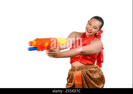 Porträt schöne Frau im Songkran Festival mit traditioneller thailändischer Tracht stehend und mit Wasserpistole mit Lächeln und Kamera auf weiß Stockfoto