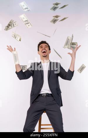 Porträt eines glücklichen jungen Mannes, der Geld wegwirft, während er isoliert im Hintergrund steht. Geld- und Vermögenskonzept. Stockfoto