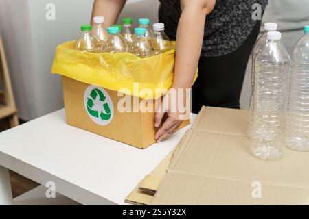 Recyceln Sie die umweltfreundliche Zero Concept Frau, die leere Plastikflasche mit gelben Mülltüten zu Hause in den Recyclingbehälter wirft Stockfoto