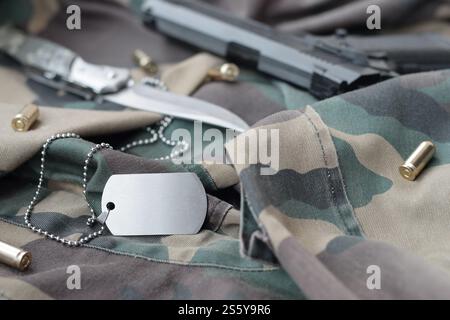 Army Dog Tag Token mit 9-mm-Kugeln und Pistole liegen auf gefaltetem grünen Stoff. Ein Set von Militärveteranen oder ein altes Trophäenkit. Armee Stockfoto