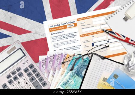 Englisch Steuerformular P60 Jahresabschluss-Zertifikat von HM Income and Customs liegt mit Büroartikeln auf dem Tisch. HMRC-Papiere und Steuerzahlungsprozess in Stockfoto