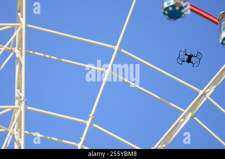 Drohne mit Fotokamera startet vom Land und fliegt für Fotos vor dem Riesenrad. Die Drohne startet vom Land und fliegt, um Fotos zu machen Stockfoto