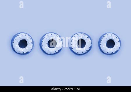 Viele kleine Plastikdonuts liegen auf einem klassischen blauen Hintergrund. Flaches Design mit minimalem Muster. Draufsicht. Viele kleine Plastikdonuts liegen auf einem Phantom Stockfoto