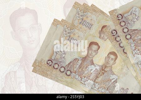 1000 thailändische Baht-Scheine liegen auf dem Hintergrund großer halbtransparenter Banknoten. Abstrakte Darstellung der Landeswährung. Geschäftskonzept. 1000 Stockfoto