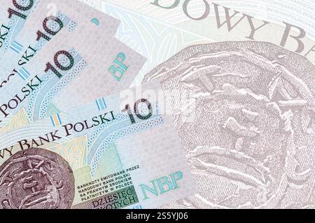 10 polnische Zloty-Scheine liegen im Stapel auf dem Hintergrund großer halbtransparenter Banknoten. Abstrakter Geschäftshintergrund mit Kopierraum. 10 polnischer Zloty Stockfoto