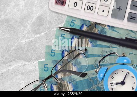 5 kanadische Dollarscheine und Taschenrechner mit Brille und Stift. Geschäftsdarlehen oder Steuerzahlung Saisonkonzept. Finanzplanung und Zeit für die Zahlung von Steuern. Stockfoto