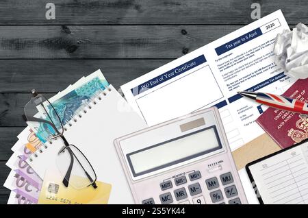Englisch Steuerformular P60 Jahresabschluss-Zertifikat von HM Income and Customs liegt mit Büroartikeln auf dem Tisch. HMRC-Papiere und Steuerzahlungsprozess in Stockfoto