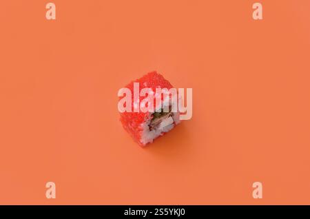 California Maki Sushi Rolle mit Kaviar und masago auf orangem Hintergrund Nahaufnahme. Minimalistischer Flachbildschirm mit Blick von oben mit japanischem Essen. Kalifornien Maki Stockfoto