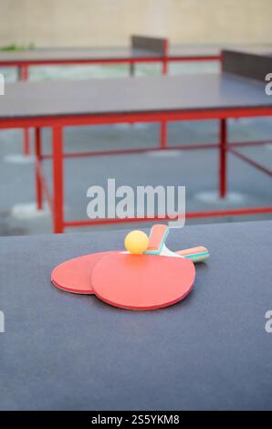 Schläger und Ball aus nächster Nähe auf dem Ping-Pong-Tisch im Sportplatz im Freien. Aktivsport und körperliches Trainingskonzept. Schläger und Ball auf dem Ping-Pong-Tisch Stockfoto