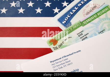 Die Green Card mit Wohnsitz in den Vereinigten staaten aus der DV-Lotterie mit Sozialversicherungsnummer liegt mit USCIS-Umschlag auf der US-Flagge in Nahaufnahme. USA Stockfoto