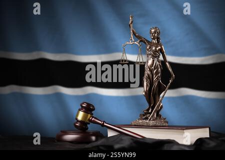 Botswana-Flagge mit Statue der Justizdame, Verfassung und Richterhammer auf schwarzem Vorhang. Urteilsbegriff und Bestrafung. Botswana Flagge mit Stockfoto