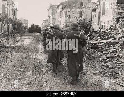 Eine Gruppe deutscher Soldaten folgt einem schweren Panzer PZ.Kpfw. VI «Tiger - auf den Straßen der zerstörten italienischen Stadt, 1944. - Historisches Dokument, Fotograf unbekannt Stockfoto