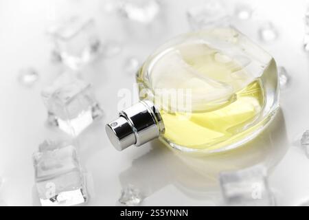 Weibliche Parfümflasche, objektive Fotografie der Parfümflasche in Eiswürfeln und Wasser auf weißem Tisch. Blick von oben. Modellbild Produktfoto, Stockfoto