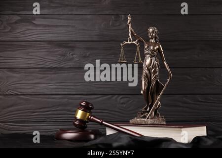 Die Statue der Gerechtigkeit - Lady Justice oder Justitia die römische Göttin der Gerechtigkeit. Statue auf braunem Buch mit Richter-Hammer. Konzept des Gerichtsverfahrens, Stockfoto