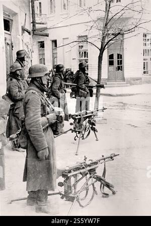 Wehrmachtssoldaten in Feodosia, Krim. Ein Soldat, der neben einem Baum steht, ist mit einem halbautomatischen Gewehr SVT bewaffnet, in der Mitte zwei deutsche Maschinengewehre MG-34 - Historisches Dokument, Fotograf unbekannt Stockfoto
