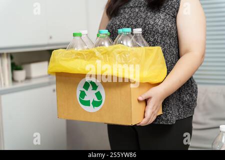 Recyceln Sie die umweltfreundliche Zero Concept Frau, die leere Plastikflasche mit gelben Mülltüten zu Hause in den Recyclingbehälter wirft Stockfoto