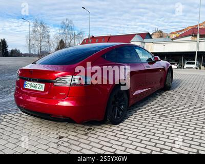 Kiew, Ukraine - 14. Januar 2025: Ein leuchtend rotes Tesla Model S 75D Elektrofahrzeug parkt in einer offenen Umgebung mit moderner Umgebung. Stockfoto