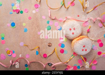 Farbenfroher Karneval- oder Partyhintergrund mit Donuts, Streamer und Konfetti Stockfoto