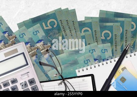 5 kanadische Dollarscheine und Taschenrechner mit Brille und Stift. Steuerzahlungssaisonkonzept oder Investitionslösungen. Finanzplanung oder Buchhalter Stockfoto