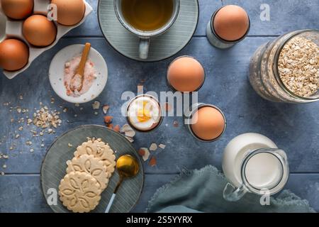 Frühstück mit gekochten Eiern, einer Tasse Tee, Milch und Haferkeksen Stockfoto