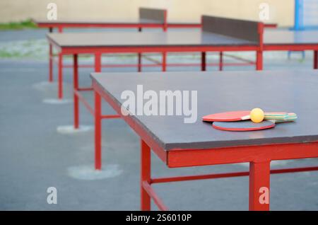 Schläger und Ball aus nächster Nähe auf dem Ping-Pong-Tisch im Sportplatz im Freien. Aktivsport und körperliches Trainingskonzept. Schläger und Ball auf dem Ping-Pong-Tisch Stockfoto