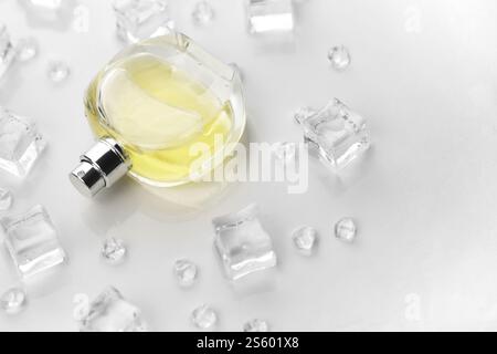 Weibliche Parfümflasche, objektive Fotografie der Parfümflasche in Eiswürfeln und Wasser auf weißem Tisch. Blick von oben. Modellbild Produktfoto, Stockfoto