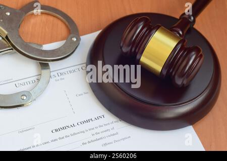 Justizhammer und Strafanzeige leeres Dokument mit Polizeihandschellen aus nächster Nähe. Justizhammer und Strafanzeige bei der Polizei Stockfoto