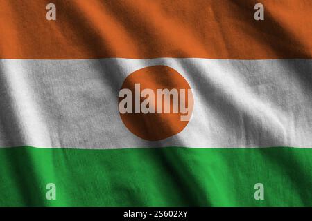Niger-Flagge mit großen Falten, die dicht oben unter dem Studio-Licht winken. Die offiziellen Symbole und Farben im Stoffbanner. Niger-Flagge mit großen Falten Stockfoto