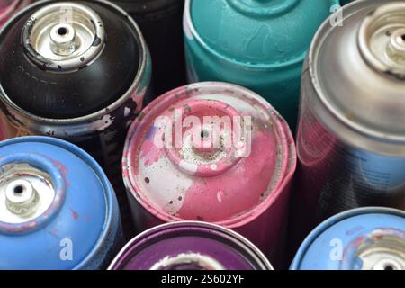 Große Anzahl gebrauchter, farbenfroher Spraydosen mit Aerosolfarbe, die auf der behandelten Holzoberfläche in der Künstler-Graffiti-Werkstatt liegen. Dreckig und Stockfoto