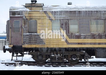 Detaillierte Foto von einem gefrorenen Auto Personenzug mit Eiszapfen und Eis auf seiner Oberfläche. Bahn in der kalten Jahreszeit Stockfoto
