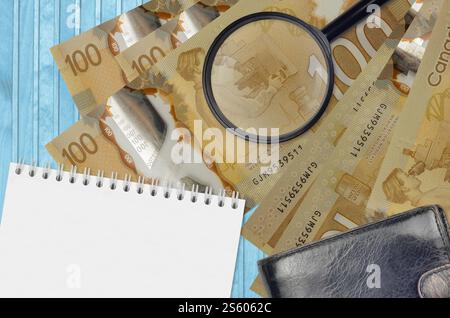 100 kanadische Dollar-Scheine und Lupe mit schwarzer Tasche und Notizblock. Das Konzept der Geldfälschung. Suchen Sie nach Unterschieden in Details auf Stockfoto