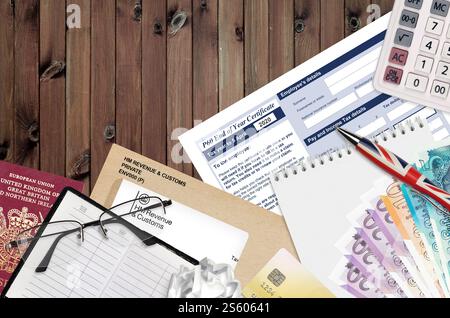 Englisch Steuerformular P60 Jahresabschluss-Zertifikat von HM Income and Customs liegt mit Büroartikeln auf dem Tisch. HMRC-Papiere und Steuerzahlungsprozess in Stockfoto