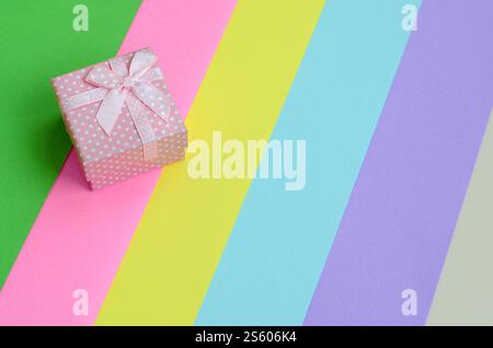Kleine rosa Geschenkkarton liegen auf Textur Hintergrund der Mode Pastell rosa, blau, grün, gelb, violett und beige Papier in minimalen Begriff. Zusammenfassung Stockfoto