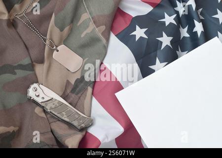 Army Dog Tag Token und Messer liegt auf Old Camouflage Uniform und gefalteter United States Flag. Hintergrund für das Design des Militärtags. Army Dog Tag Token und Stockfoto