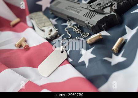 Army Dog Tag Token mit 9-mm-Kugeln und Pistole liegen auf gefalteter US-Flagge. Ein Satz von Veteranen des US-Militärs oder ein Trophäenkit für alte Zwecke. Armeehund Stockfoto