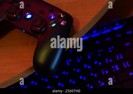 Modernes Gamepad mit pc-Tastatur auf dem Tisch in dunkler Spielzimmerszene aus nächster Nähe. Lassen Sie sich gemeinsam mit Freunden Videospiele spielen. Modernes Gamepad Stockfoto