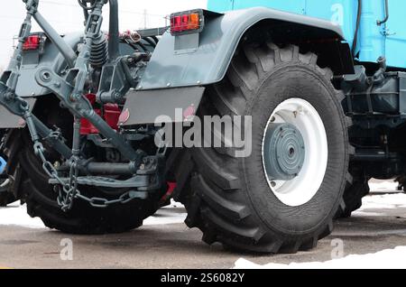 Räder der Rückansicht des neuen Traktors bei Schnee. Rückansicht des landwirtschaftlichen Fahrzeugs. Räder der Rückansicht des neuen Traktors bei Schnee. Stockfoto
