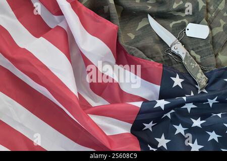 Army Dog Tag Token und Messer liegt auf Old Camouflage Uniform und gefalteter United States Flag. Hintergrund für das Design des Veterans Day. Army Dog Tag Token und Stockfoto