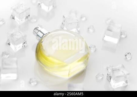 Weibliche Parfümflasche, objektive Fotografie der Parfümflasche in Eiswürfeln und Wasser auf weißem Tisch. Blick von oben. Modellbild Produktfoto, Stockfoto
