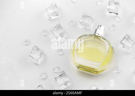 Weibliche Parfümflasche, objektive Fotografie der Parfümflasche in Eiswürfeln und Wasser auf weißem Tisch. Blick von oben. Modellbild Produktfoto, Stockfoto