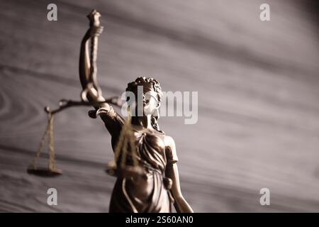 Die Statue der Gerechtigkeit - Lady Justice oder Justitia die römische Göttin der Gerechtigkeit. Statue auf schwarzer Holzwand. Das Konzept des Gerichtsverfahrens, Gerichtssaal Stockfoto