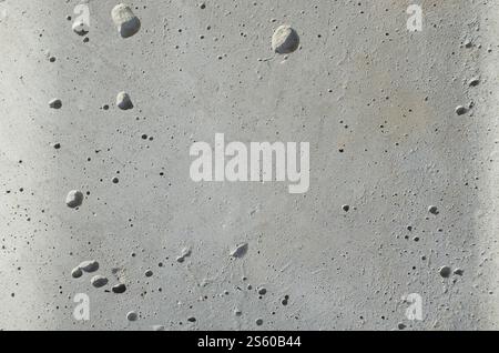 Dunkelgraue Betonstruktur, raue Zementsteinwand, Oberflächenkies der alten und schmutzigen Gebäudewand im Freien. Abstrakter urbaner Hintergrund. Dunkelgrau Stockfoto