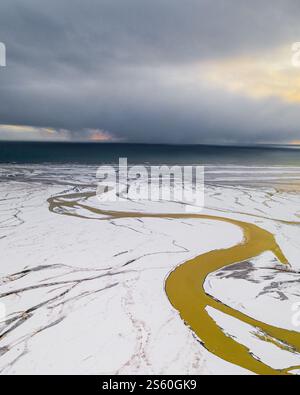 Aus der Vogelperspektive des sich windenden Flusses, der durch die verschneite Küste in Südisland führt. Stockfoto