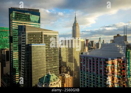 Ein pulsierendes Stadtbild von Manhattan, New York City mit modernen Wolkenkratzern während eines Sonnenuntergangs in der goldenen Stunde unter teilweise bewölktem Himmel. Stockfoto