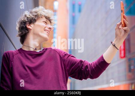 Ein lächelnder junger Mann macht ein Selfie in einer städtischen Umgebung Stockfoto