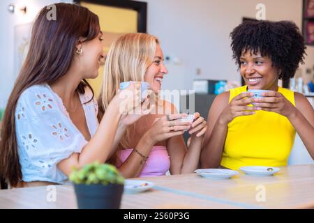 Drei Frauen genießen Kaffee und lachen in einem gemütlichen Café Stockfoto