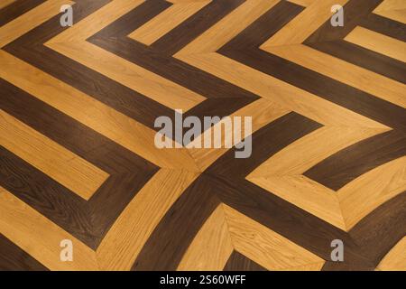 Eine detaillierte Ansicht des Holzbodens mit kontrastierenden hellen und dunklen Paneelen in geometrischem Muster Stockfoto