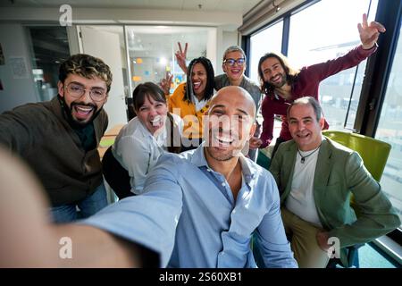 Glückliches Geschäftsteam, das gemeinsam ein Selfie im modernen Büro macht. Stockfoto
